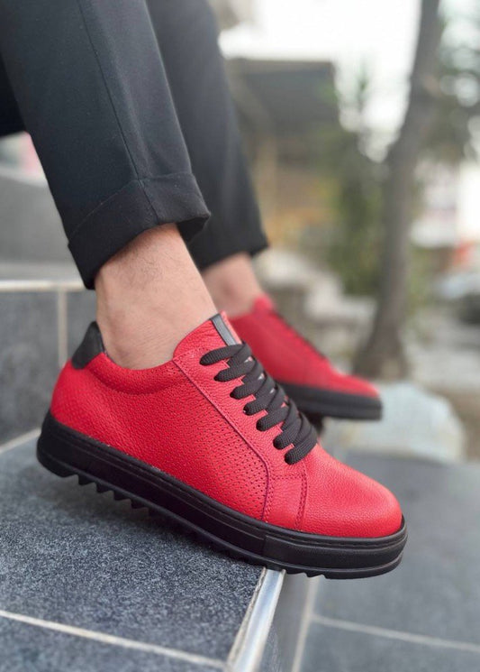 Red sneakers with black soles worn by a person on a stone surface.